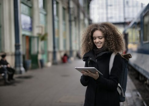 GlobalReach-cheerful-young-lady-browsing-tablet-while-waiting-for-train-2