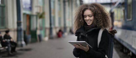 GlobalReach-cheerful-young-lady-browsing-tablet-while-waiting-for-train-2