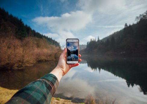 GlobalReach-man using phone by lake